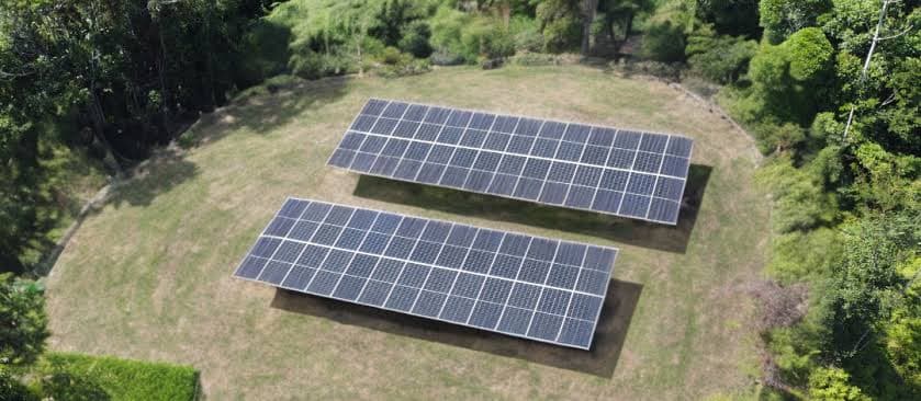 Painéis solares instalados em propriedade rural com plantações ao fundo